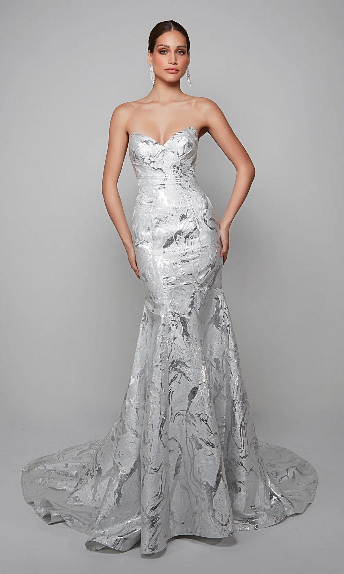 A woman poses elegantly against a plain gray background, wearing the Alyce 7055—a long white strapless dress with a fitted bodice and flared mermaid train.